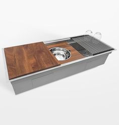 a stainless steel sink with wooden cutting board and drainer in the center on an isolated white background