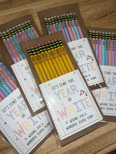 four notebooks with colored pencils in them on a wooden table next to each other