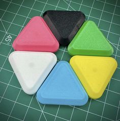 four different colored plastic shapes on a cutting board