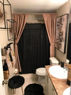 a bathroom with a black shower curtain and rugs on the floor in front of it