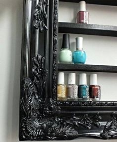 an ornate black framed mirror with nail polish bottles on the bottom shelf and shelves below it