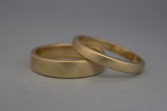 two gold wedding rings sitting next to each other