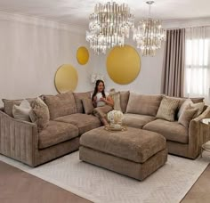 a woman sitting on top of a couch in a living room next to a chandelier