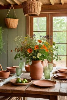 a wooden table topped with lots of plates and vases filled with flowers on top of it