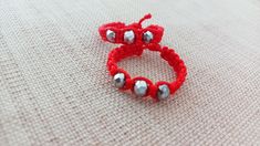 two red bracelets sitting on top of a white cloth covered table next to each other