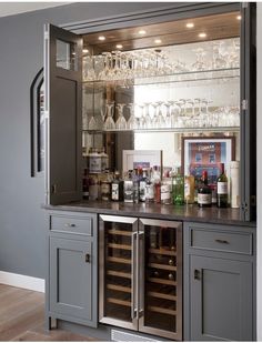 a bar with wine glasses and bottles on it in a room that is painted gray