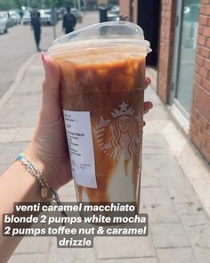 a person holding up a starbucks drink on the side of the street with words describing it