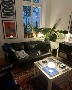 a living room with black leather couches and potted plants in the window sill