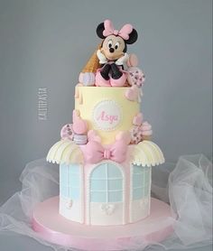 a pink and yellow cake with minnie mouse on top