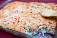 a casserole dish with rice and vegetables in it, topped with a wooden spoon