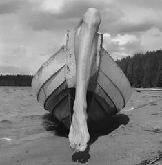 black and white photograph of a person's feet resting on a boat in the water