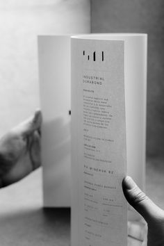 a person holding up an open book in front of a cat's paw on the table