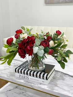 a vase filled with red and white flowers on top of a table next to a book