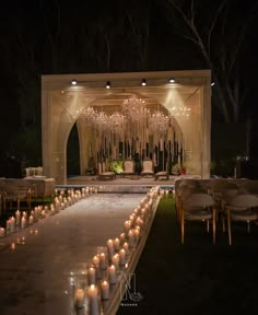 an outdoor ceremony with candles lit up on the ground and chairs set up in front of it