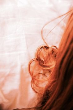 a woman laying on top of a bed with her hair blowing in the wind,