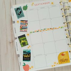 a planner with stickers on it sitting on a wooden table next to an apple