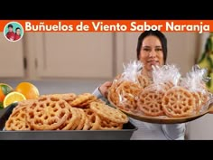 a woman holding a tray filled with cookies and oranges