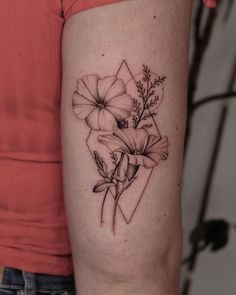 a woman's arm with flowers on it and a diamond tattoo design in the middle