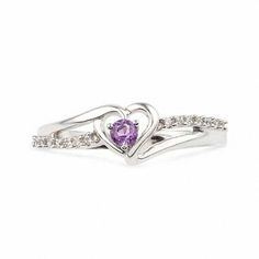 a heart shaped ring with two diamonds on the side and a purple stone in the middle