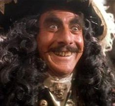 a man with long black hair wearing a pirate hat and wig smiling at the camera