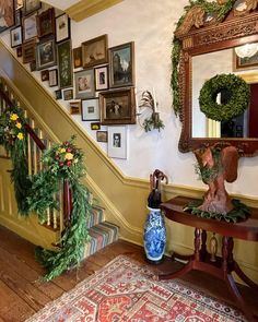 an entryway decorated for christmas with wreaths and garland on the bannisters