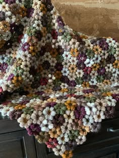 a crocheted blanket sitting on top of a dresser next to a wooden drawer