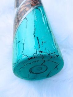 a close up of a blue glass tube on a white surface with some writing on it