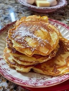 some pancakes are stacked on a plate with butter in the middle and syrup sprinkled on top