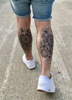 a man's legs with tattoos on them walking down the street in jeans and white sneakers