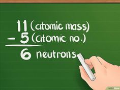 a hand writing on a blackboard with the atomic mass