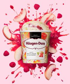 an ice cream with raspberries and sliced apples on it's side in front of a pink background