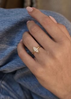 a woman's hand wearing a gold ring with a diamond on the middle finger