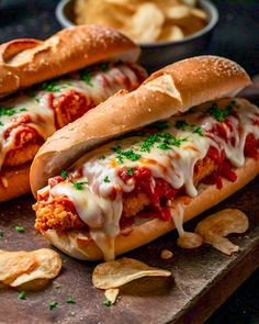 two chicken parmesan sandwiches on a cutting board with chips