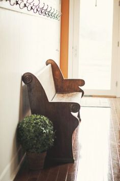 a wooden bench sitting on top of a hard wood floor next to a white door