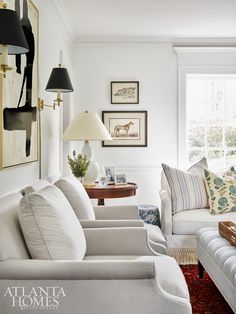 a living room with couches, lamps and pictures on the wall