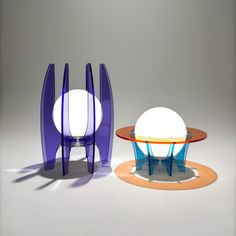 two modern glass tables with colored bases and lights on each side, in front of a gray background