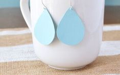 two pairs of blue tear earrings on a white mug with burlap tablecloth