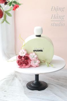 a white cake with pink flowers and a perfume bottle on it's top that says chank