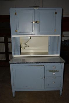 an old blue kitchen cabinet with a sink and cupboards on the top, in a garage