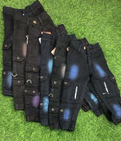 five pairs of black jeans with holes and zippers on them sitting in the grass