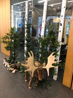 two moose statues are sitting in front of some christmas trees and other decorations on the floor