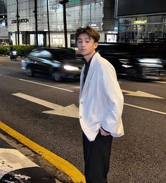 a man standing on the side of a road next to a crosswalk at night