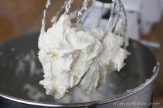 a metal bowl filled with whipped cream on top of a wooden table