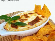 a white bowl filled with cheese and tortilla chips on top of a wooden table