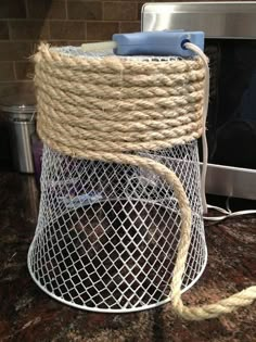 a wire basket with rope wrapped around it on top of a counter next to a microwave