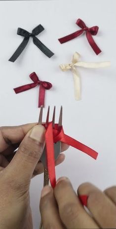 someone is cutting ribbon with scissors on a white surface and another person is holding one