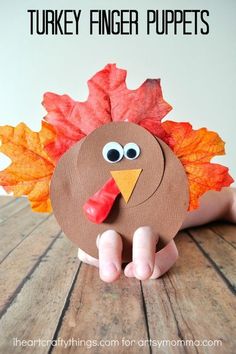 a paper plate with a turkey on it and leaves around it's head, sitting on a wooden table