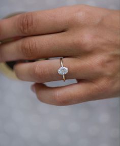 a woman's hand with a diamond ring on top of her finger and an engagement band