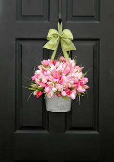 a potted plant with pink flowers hanging from it's side on a black door