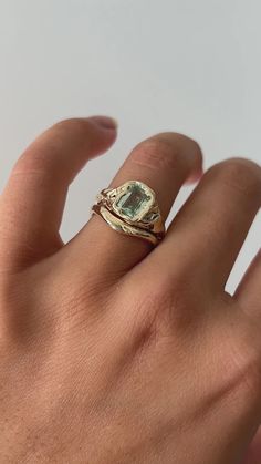 a person's hand with a gold ring and an aquamarine stone on it